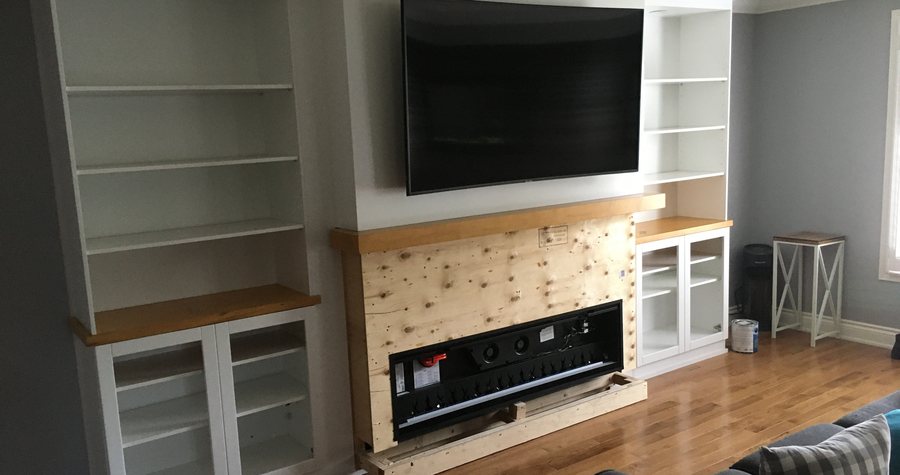 A finished built-in media wall with an integrated fireplace, TV mount and floating shelving in a living room.