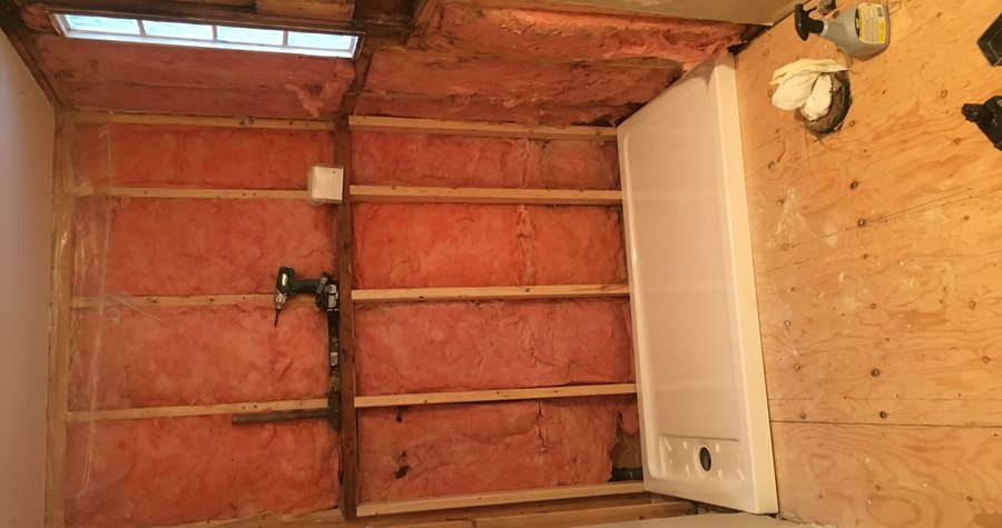 A new tub surround set into a framed bathroom wall with fresh batt insulation, before the backer board and tile go on.