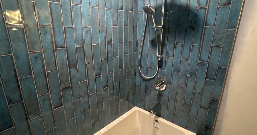A finished tub surround in a Kitchener bathroom, deep blue handmade-look tile from floor to ceiling.