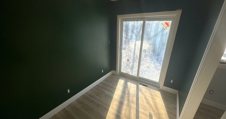 A newly finished second-storey addition bedroom in Kitchener, painted, trimmed and floored, with a sliding door to the yard.