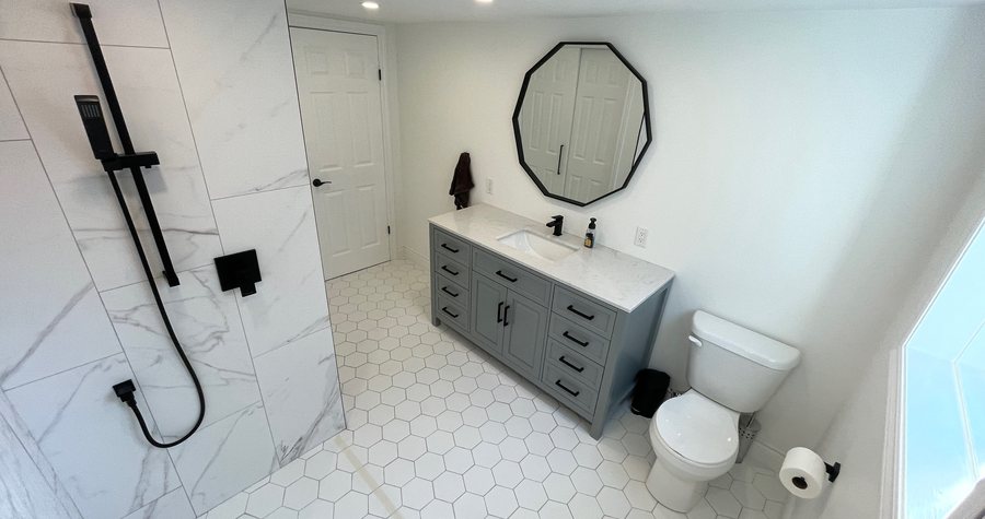 A finished bathroom shot wide enough to read the clear floor space around the vanity, toilet and glass shower.