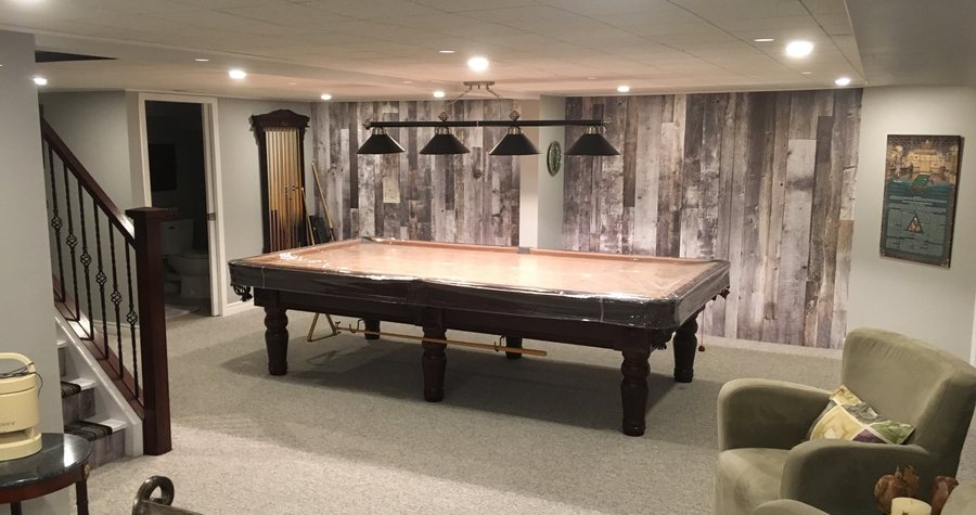 A finished basement recreation room with a feature wood wall, pool table and built-in lighting.