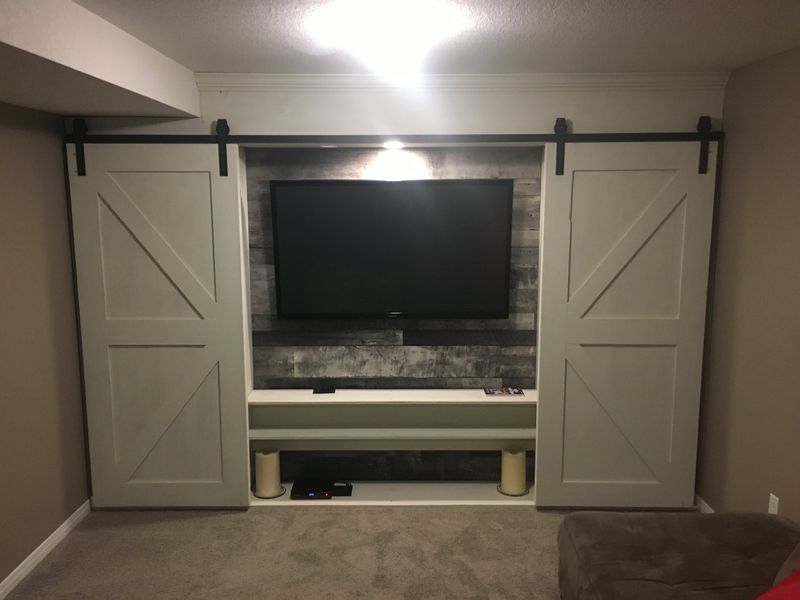 Finished basement media wall flanked by sliding barn doors
