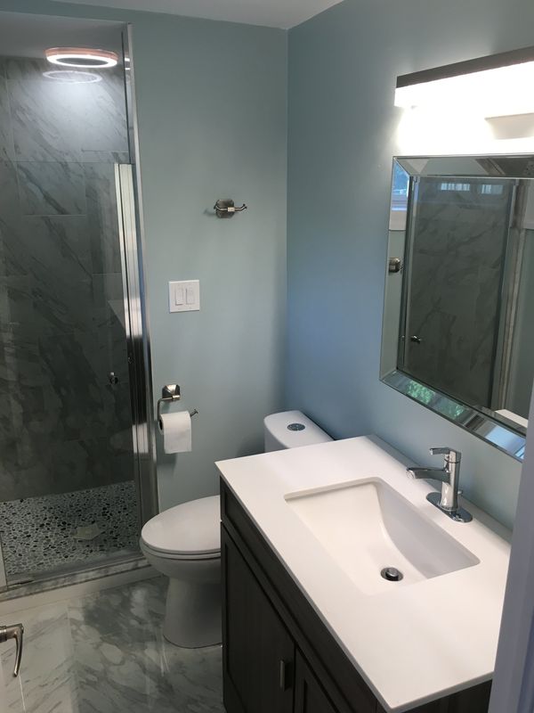 Compact bathroom with dark stone shower tile and a floating vanity