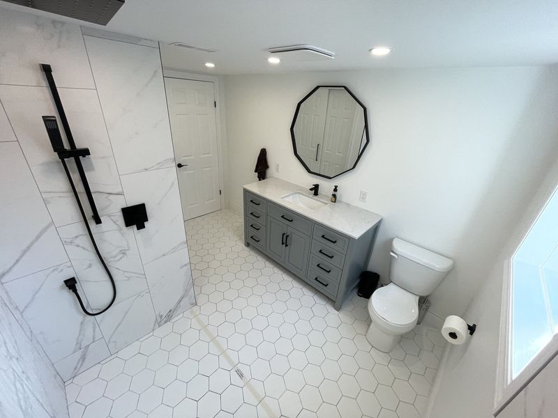 Bathroom with hexagon floor tile, octagonal mirror and a grey shaker vanity