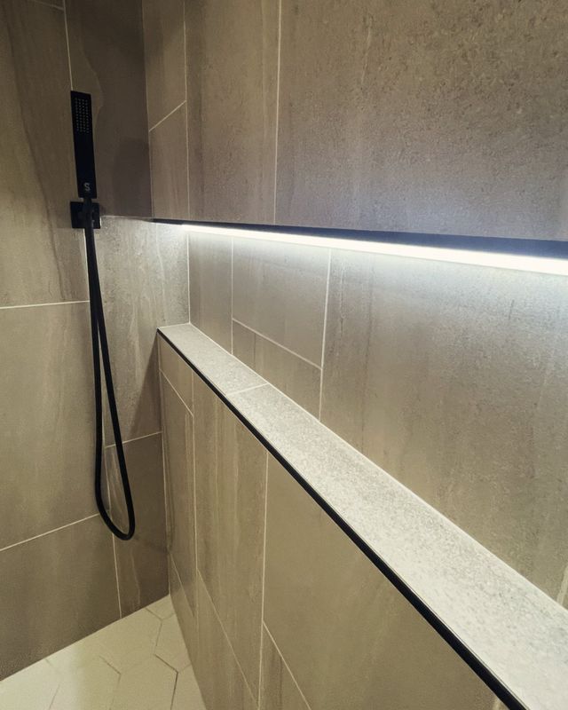 Detail of a stone shower niche with concealed LED strip lighting