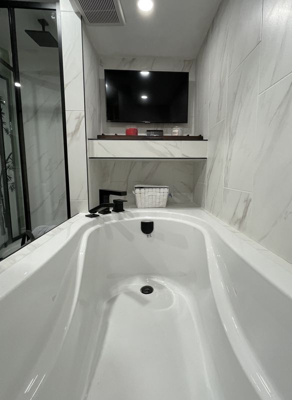 Freestanding soaker tub against large-format marble tile