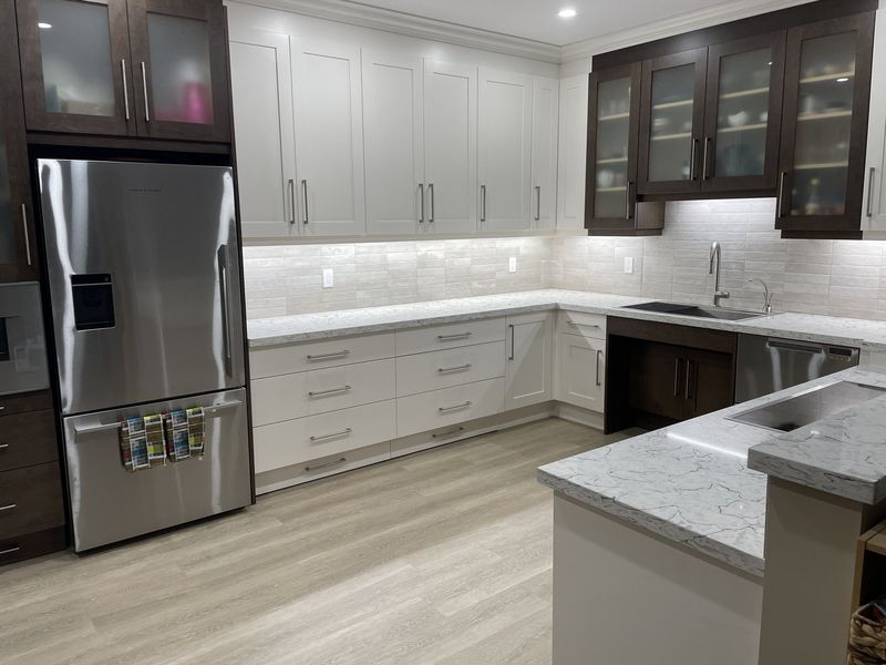 Two-tone shaker kitchen with marble waterfall island and stainless appliances