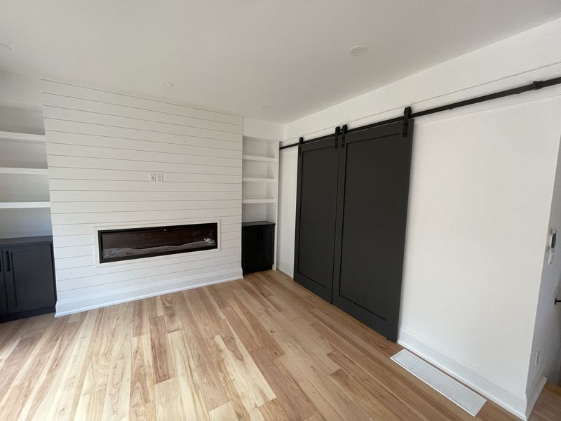 Shiplap wall with a linear fireplace and a black sliding barn door