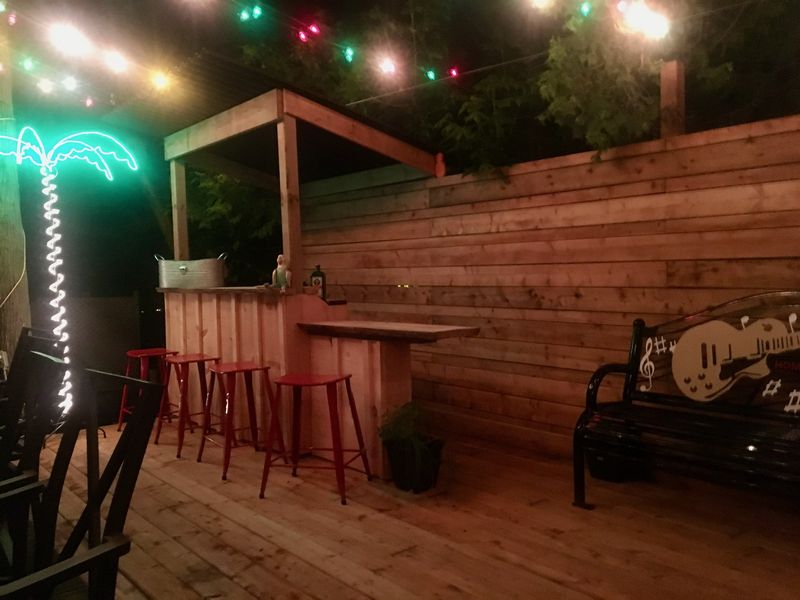 Covered outdoor bar with cedar cladding and string lighting at night