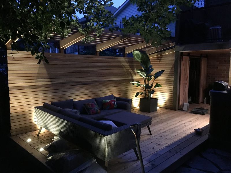 Composite deck with built-in lounge seating and low-voltage lighting at dusk