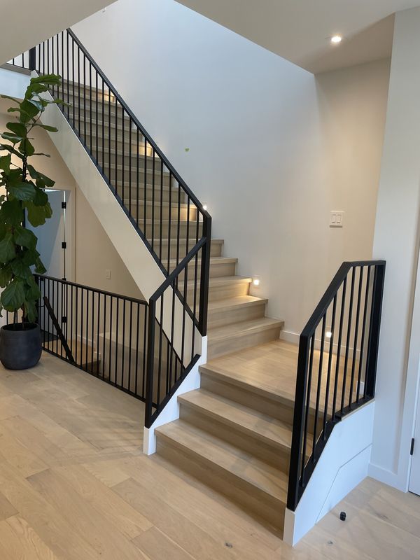 Light oak staircase with a black metal railing and open landing